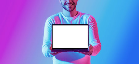 Millennial smiling guy shows laptop with blank luminous screen, croppedの写真素材