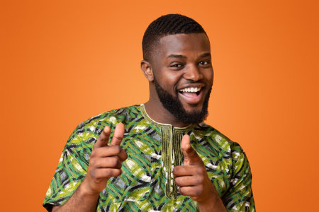 Playful african guy indicating to camera over yellow background