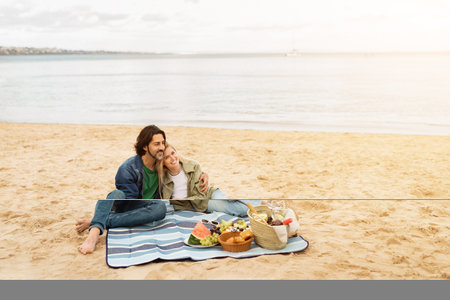 Couple enjoys a romantic picnic on the beach at sunset with delicious foodの写真素材