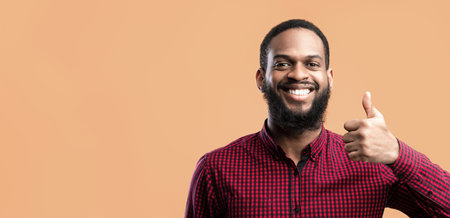 Happy black man gesturing thumbs up and smilingの写真素材