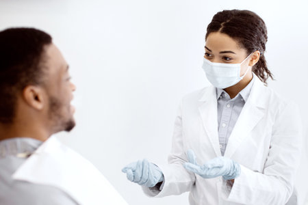 Dental Check Up. Black Stomatologist Lady Consulting Male Patient In Clinicの写真素材