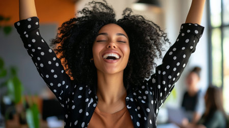Joyful woman celebrating success in a modern office environment during daylightの素材