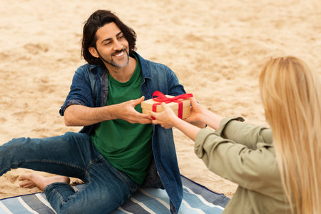 Couple enjoying a beach day exchanging gifts on a sunny afternoonの写真素材