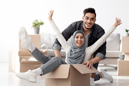 Positive muslim family playing with packing supplies while moving