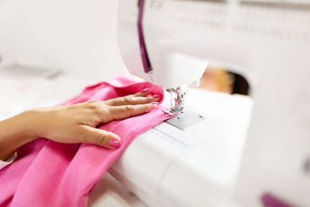 Creative designer working diligently on pink fabric at her sewing machine