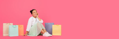 Beautiful young asian woman sitting on floor surrounded by shopping bagsの写真素材