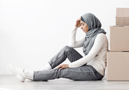 Upset middle-eastern family sitting separated by paper boxes on floorの写真素材