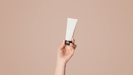 Unrecognizable woman showing tube with hand cream over pink background, closeupの写真素材