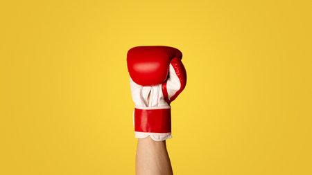Close up of sportsman wearing boxing glove on orange backgroundの写真素材