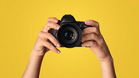 Closeup of photographer pointing DSLR camera at screen, blue background. Panorama