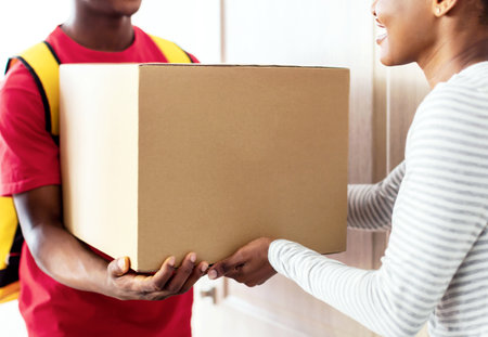 Professional Courier Delivering Parcel To African American Lady At Homeの写真素材