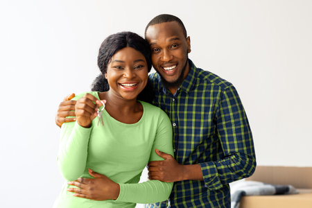 Happy Owners. Cheerful Black Spouses Posing With Keys From Their New Homeの写真素材