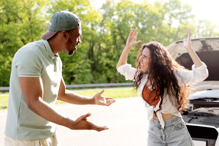 Millennial multiracial couple having conflict, shouting at each other on road near broken car
