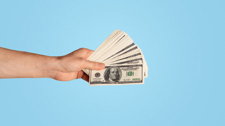 Closeup of successful guy holding US money on light background