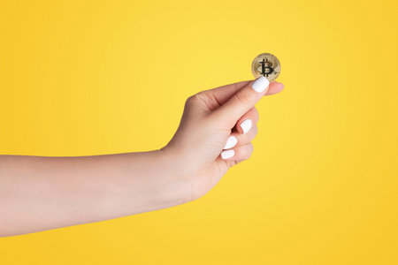 Close up of millennial woman holdng bitcoin on light backgroundの写真素材