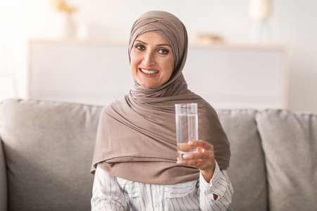 Muslim Woman Posing Holding Glass Of Water Drinking At Homeの写真素材