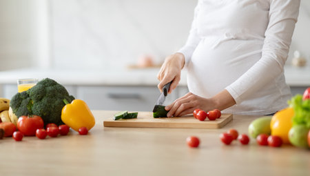 Pregnant woman preparing fresh vegetables in a kitchen for healthy eatingの写真素材