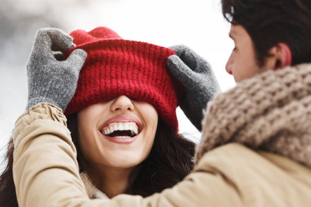 Man Putting His Cap On Laughing Girlfriend Standing In Winter Forestの写真素材