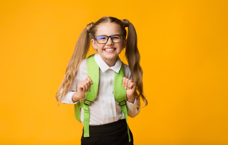 Happy Schoolgirl Smiling Posing At Camera, Yellow Background, Studio Shotの写真素材