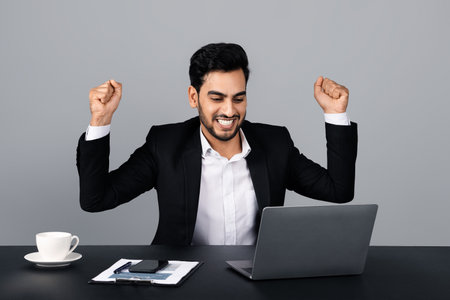 Businessman celebrating a success while working in a modern studio settingの写真素材