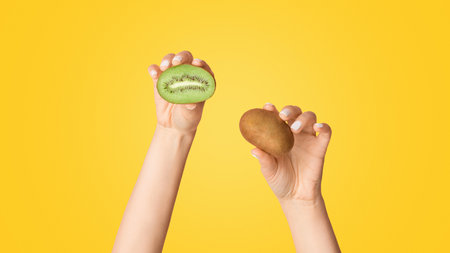 Closeup of girl holding yummy kiwi fruits on pink background, panoramaの写真素材