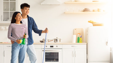 Young asian couple mopping floor in kitchenの写真素材