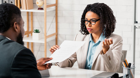 Serious personnel manager taking resume from young job applicant on work interview at modern company...