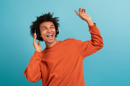 Young man enjoying music with headphones against bright blue background