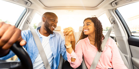 Happy black couple enjoying drive on car, holding hands