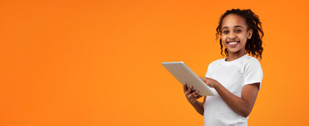 Black girl standing with tablet at yellow studioの写真素材