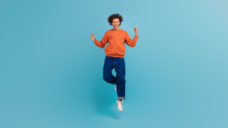 Young man enjoying a joyful moment with curly hair against a blue backdrop