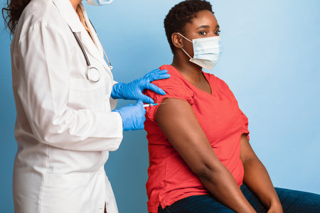 African American Lady In Mask Receiving Antiviral Vaccine Shot, Studioの写真素材