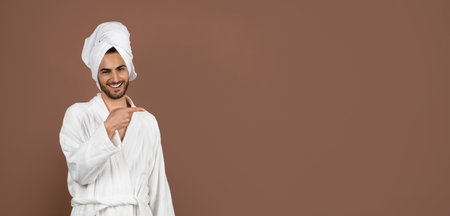 Young man in a bathrobe showing excitement in an indoor settingの写真素材
