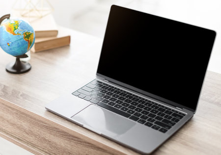 Female Travel Agent Using Laptop With Empty Screen In Officeの写真素材