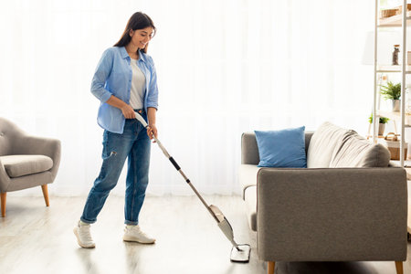 Portrait of smiling woman cleaning floor with spray mop