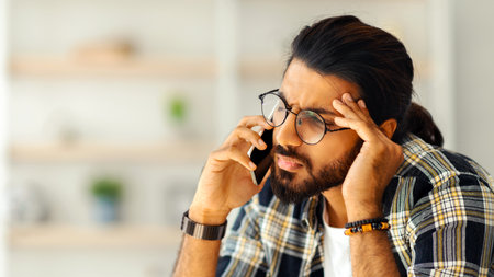 Upset middle-eastern guy having phone conversation, home interior