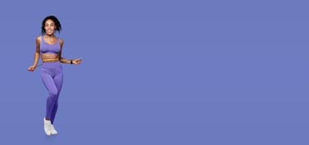 A woman exercising in purple activewear against a vibrant blue backgroundの写真素材