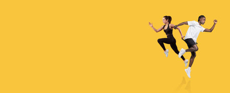 Energetic young athletes running against a vibrant yellow backgroundの写真素材