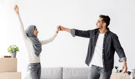 Joyful arab man and woman dancing in their new houseの写真素材