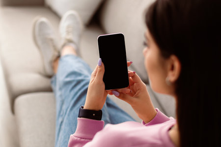 Back view of woman using phone with empty mockup screenの写真素材