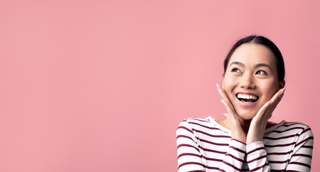 Excited Asian Woman Touching Face And Looking At Copy Space With Amazementの写真素材