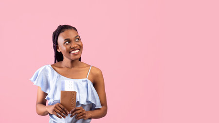 Happy young black woman with passport and plane tickets looking aside at free space, traveling abroad on pink backgroundの写真素材