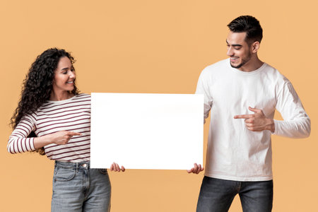 Check This. Smiling Arab Man And Woman Pointing At Blank White Placardの写真素材