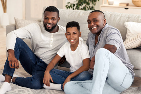 Cheerful Black Family Sitting On Floor At Home Posing To Cameraの写真素材