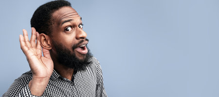 Curious handsome afro guy holding hand near earの写真素材