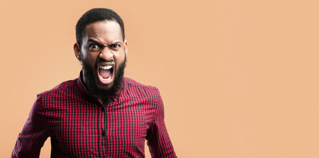 Angry afro man screaming at yellow studioの写真素材