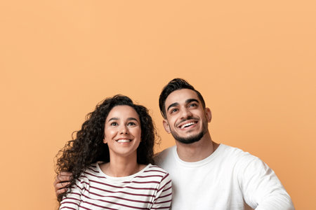 Dreamy Young Arab Couple Sitting On Floor And Looking At Copy Spaceの写真素材