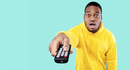 Shocked African Man Pointing Television Remote Controller Switching Channels, Studio