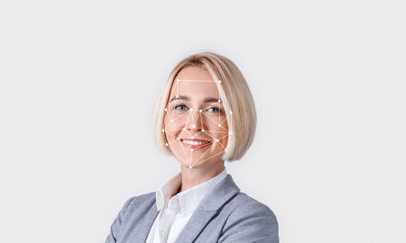 A person with short blonde hair is smiling confidently in a professional outfit