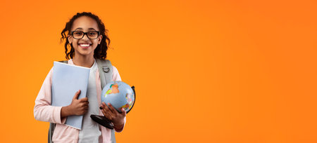 Cheerful young black girl holding Earth world globe and notebook